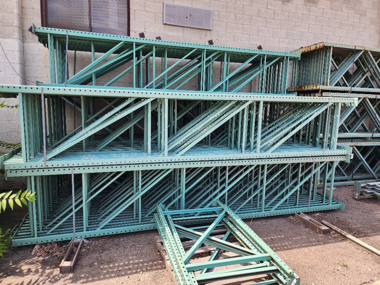 Green metal shelving units stacked against a building exterior
