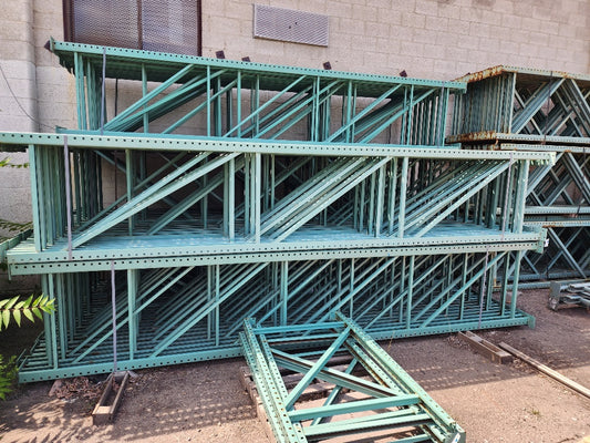 Green metal shelving units stacked against a building exterior